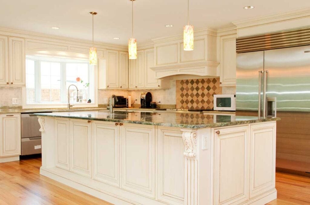Spacious kitchen with white cabinetry, granite countertops, stainless steel appliances, pendant lights, and hardwood floors.